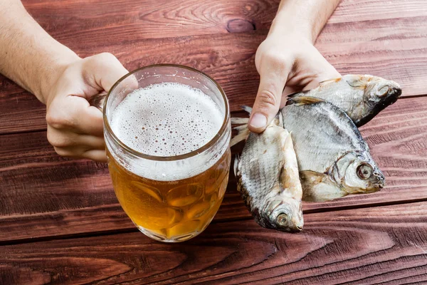 Mano con vaso de cerveza y pescado seco . — Foto de Stock