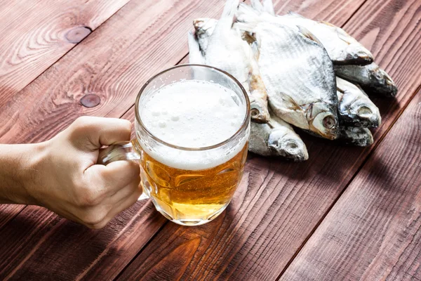 Mano con vaso de cerveza y pescado seco . — Foto de Stock