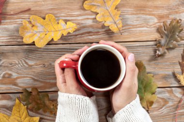 Sonbahar arka planında elinde bir fincan kahve tutan kadın..