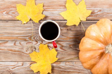Kahve fincanı, defter, sonbahar yaprakları ve kabak.