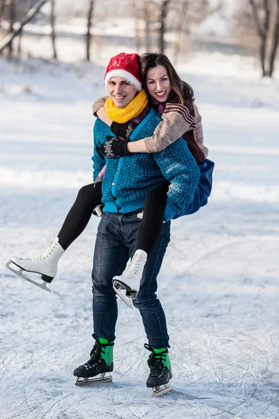 Pareja feliz divirtiéndose patinaje sobre hielo en pista al aire libre . — Foto de Stock