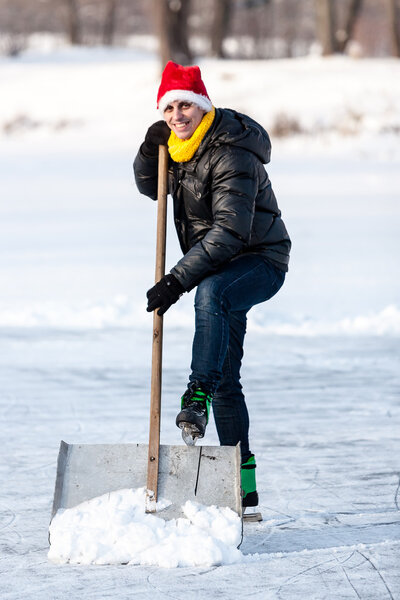 Man wearing skates working with snow shovel.