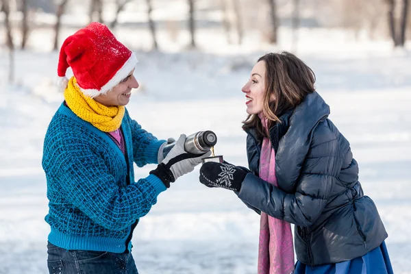 Glückliches Paar hat Spaß und trinkt heißen Tee auf Eisbahn im Freien. — Stockfoto