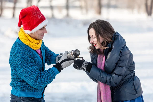 Happy couple having fun and drinking hot tea on rink outdoors. — Stock Photo, Image