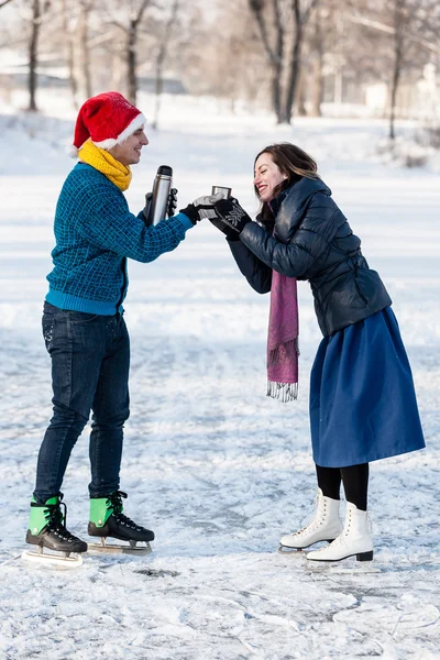 Lyckliga par att ha roligt och dricka varm te på isbana utomhus. — Stockfoto