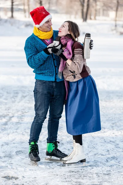 Glückliches Paar hat Spaß und trinkt heißen Tee auf Eisbahn im Freien. — Stockfoto