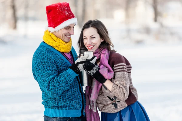 Couple heureux s'amuser et boire du thé chaud sur la patinoire à l'extérieur . — Photo