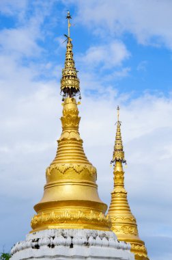 Arka planda mavi bulutlu gökyüzü olan altın pagodalar