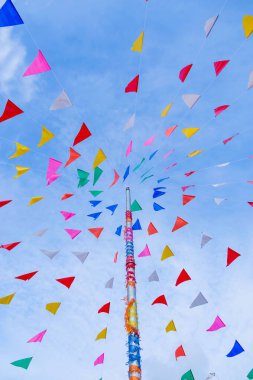 Tayland tarzı süslü parti bayrağının canlı rengi mavi gökyüzü ve beyaz bulutlu süslü bir direğin üzerindeki süslemeleri soyar.