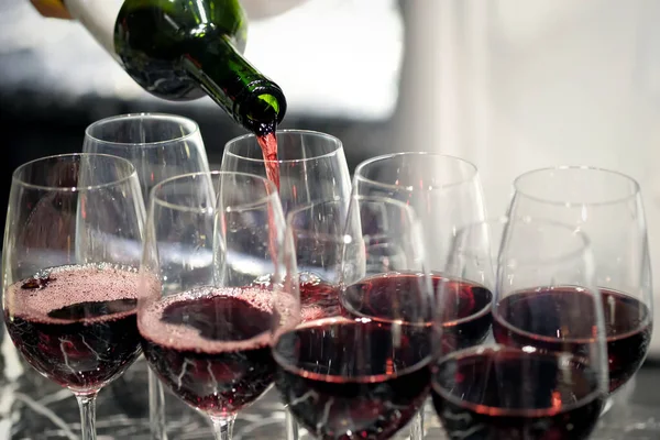 pouring wine in many glasses for dinner party