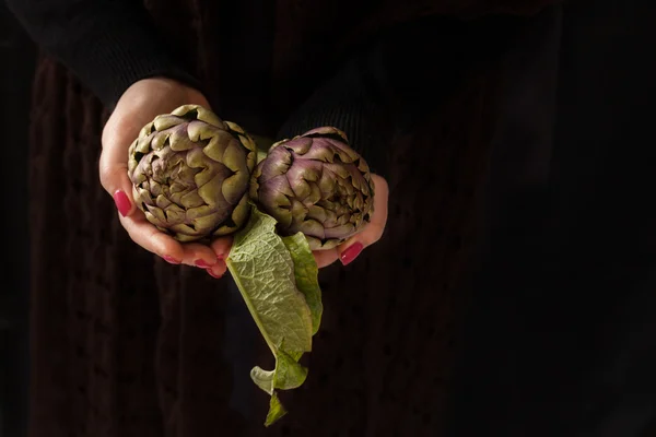 Ruwe artisjokken In handen — Stockfoto