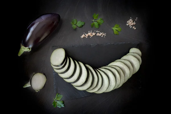 Auberginenscheiben auf schwarzem Tisch — Stockfoto