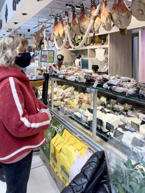 Bracciano, Roma, İtalya - 26 Mart 2021 'de Gros zincirinin bir süpermarketinde paskalya yemeği için sandviç ve peynir alan kadın.