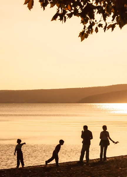 Familiensilhouette am Strand in der Abenddämmerung. — Stockfoto