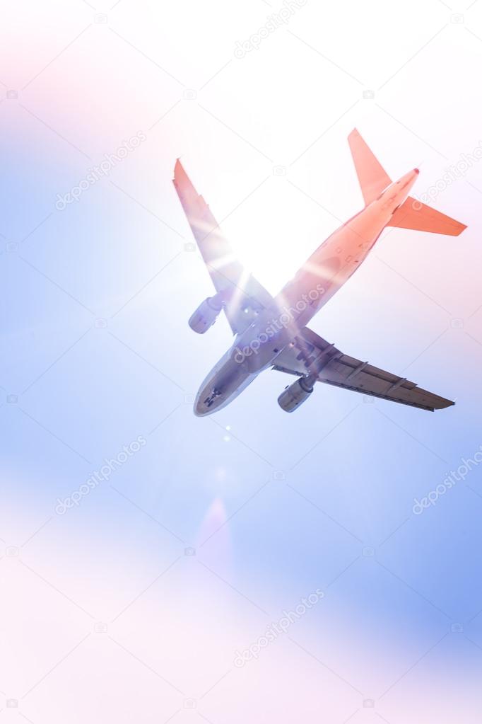 Commercial airliner flying above clouds with blue sky in background