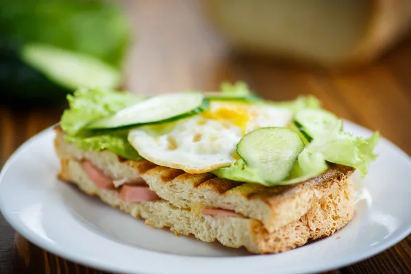 Sanduíche com salsicha, queijo, alface e ovos — Fotografia de Stock