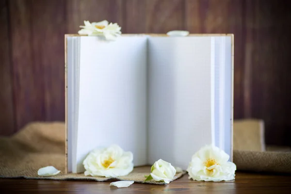Buquê de belas rosas brancas e caderno em branco — Fotografia de Stock
