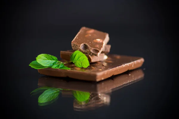 Chocolate negro dulce con nueces sobre fondo negro —  Fotos de Stock