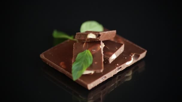 Γλυκιά μαύρη σοκολάτα με ξηρούς καρπούς σε μαύρο φόντο — Αρχείο Βίντεο