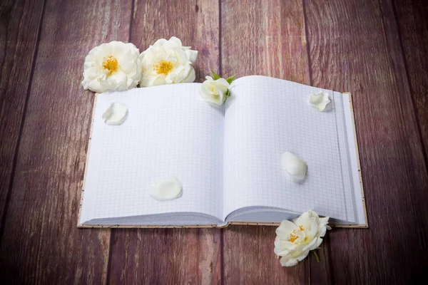 Csokor Gyönyörű Fehér Rózsa Üres Notebook Egy Asztalon — Stock Fotó