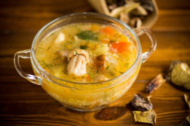 Sebze çorbası, ahşap bir masada cam bir kasede porcini mantarı.