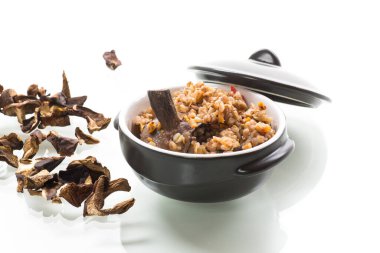 Beyaz arka planda izole edilmiş seramik kasede kurutulmuş organik orman mantarlı haşlanmış karabuğday.