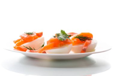 Beyaz arka planda izole edilmiş tuzlanmış somon parçalarıyla kaynamış yumurta parçaları.