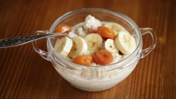 Masak oatmeal manis dengan aprikot kering dan pisang dalam mangkuk — Stok Video