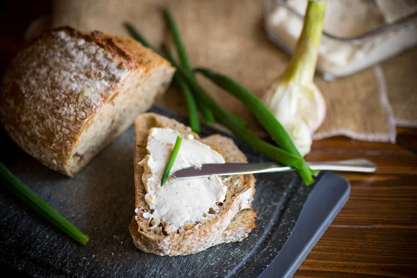 Homemade buckwheat bread with garlic cheese spread on a wooden table