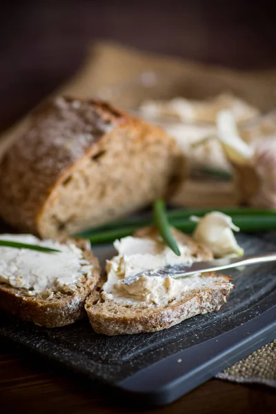 Homemade buckwheat bread with garlic cheese spread on a wooden table