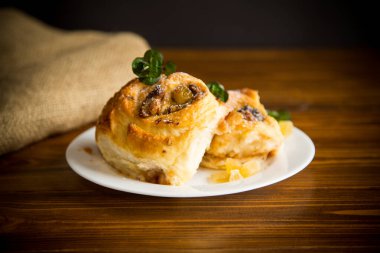 Reçelli tatlı kıvırcık çörek, tabakta pudra şekerli kuru üzüm.