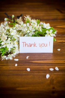 Teşekkür kartı ve çiçek açan bahar dalı, ahşap arka planda.