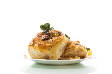 Reçelli tatlı kıvırcık çörek, tabakta pudra şekerli kuru üzüm.