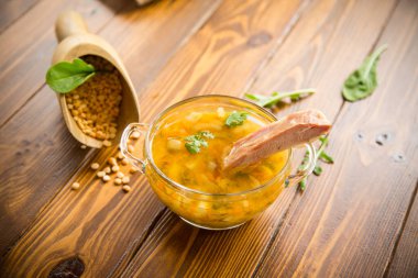 Pişmiş bezelye çorbası, pirzola, ahşap bir masada bir tabakta tütsülenmiş.