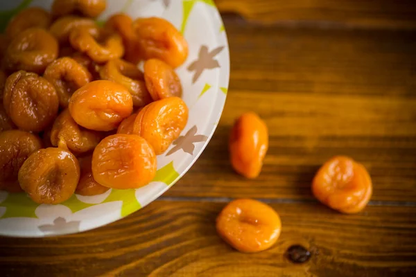 Delicious dried apricots in a bowl on a wooden table — Stock Photo, Image