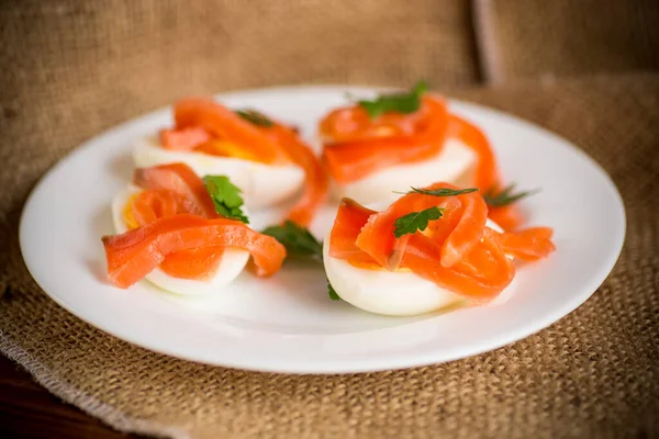 Mitades de huevos cocidos con trozos de salmón salado —  Fotos de Stock