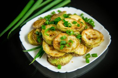 Siyah arka planda taze otlarla çevrili kızarmış kabak.