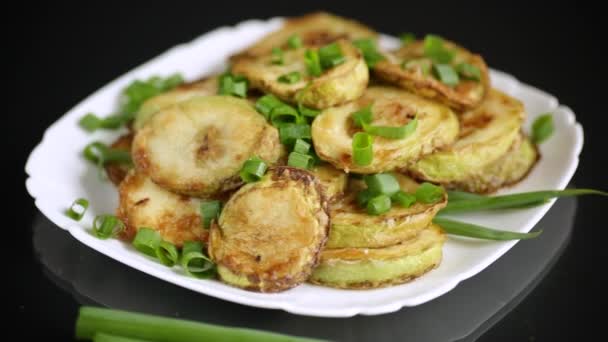 Gebratene Zucchini im Kreis mit frischen Kräutern in einem Teller auf einem schwarzen — Stockvideo