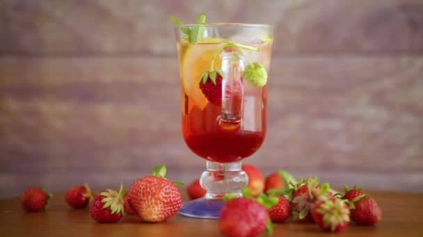 Verfrissende koele aardbeienlimonade met citroen, ijs en munt in een glas — Stockvideo