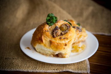 Reçelli tatlı kıvırcık çörek, tabakta pudra şekerli kuru üzüm.
