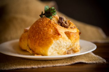 Reçelli tatlı kıvırcık çörek, tabakta pudra şekerli kuru üzüm.