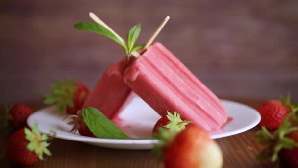 Gelato alla fragola fatto in casa su un bastoncino di fragole fresche in un piatto — Video Stock