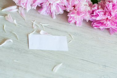 Tahta bir arka planda çiçek açan pembe şakayık dalları.