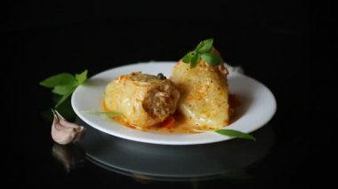 Biberli et ve pirinçle doldurulmuş siyah arka planda bir tabakta.