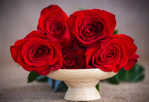 黄麻布の古いテーブルに赤いバラの美しい花束 — ストック写真
