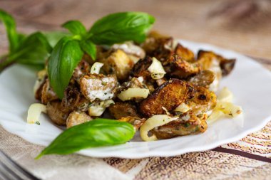 Appetizing eggplant pieces with sauce and fresh basil leaves.