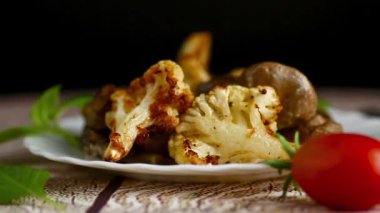 Beyaz seramik tabakta servis edilen kavrulmuş karnabahar ve mantar..