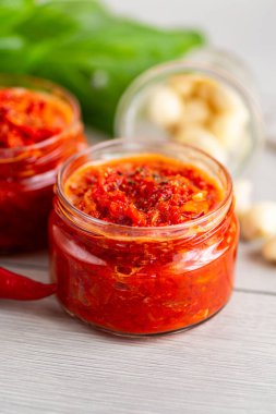 Kavanozlarda taze malzemelerle birlikte parlak kırmızı biber sosu.