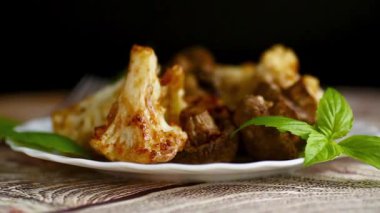 Beyaz seramik tabakta servis edilen kavrulmuş karnabahar ve mantar..