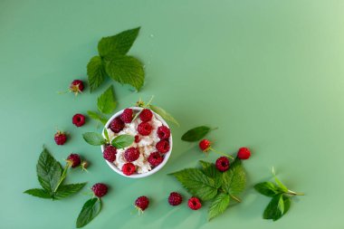 Süzme peynirli beyaz kase ve masada ahududu..